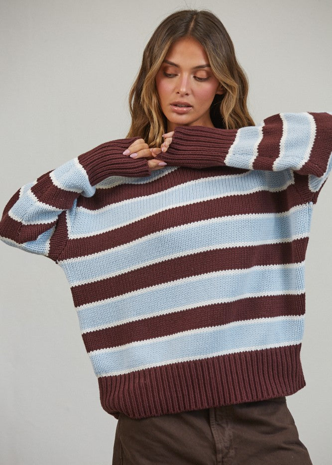 Woman wearing a striped sweater with brown and blue horizontal stripes against a plain background