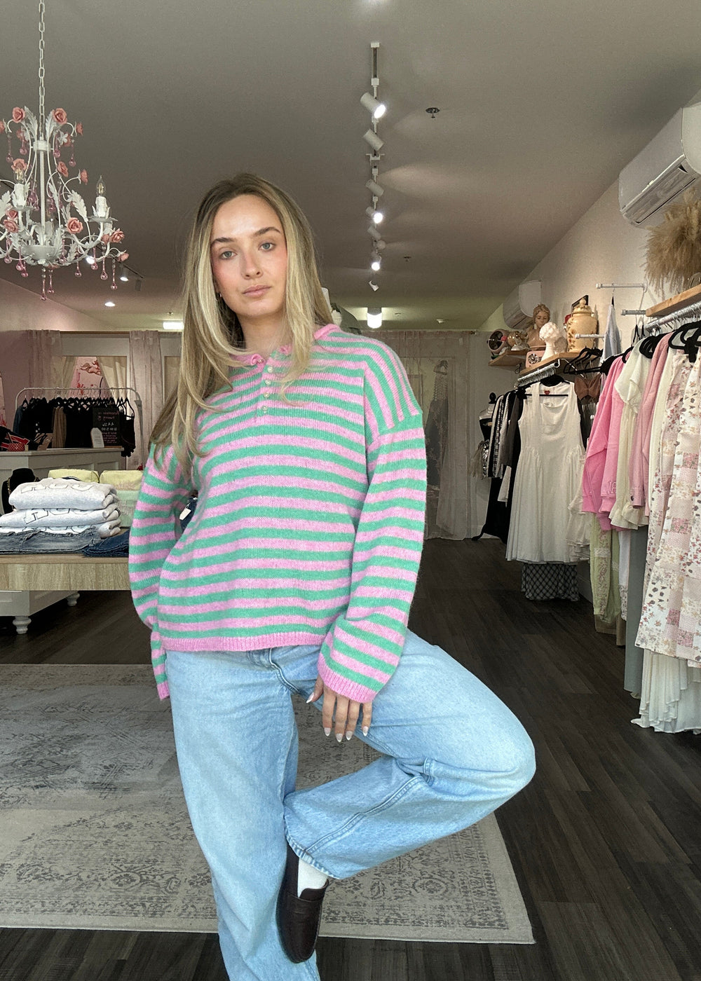 Woman in a striped sweater and jeans standing in a clothing store.