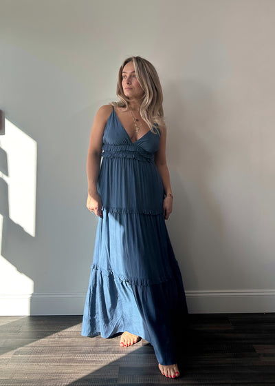 Flowy tiered maxi dress with plunging V-neckline, ruffle details, adjustable spaghetti straps, and hidden side pockets.