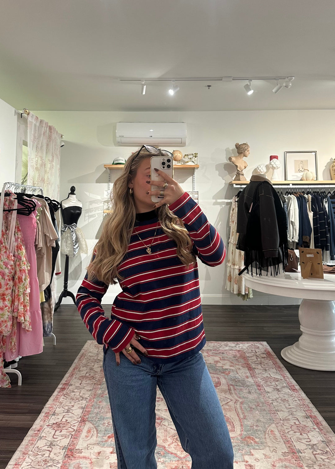 Person wearing a red and blue striped sweater and jeans in a clothing store.