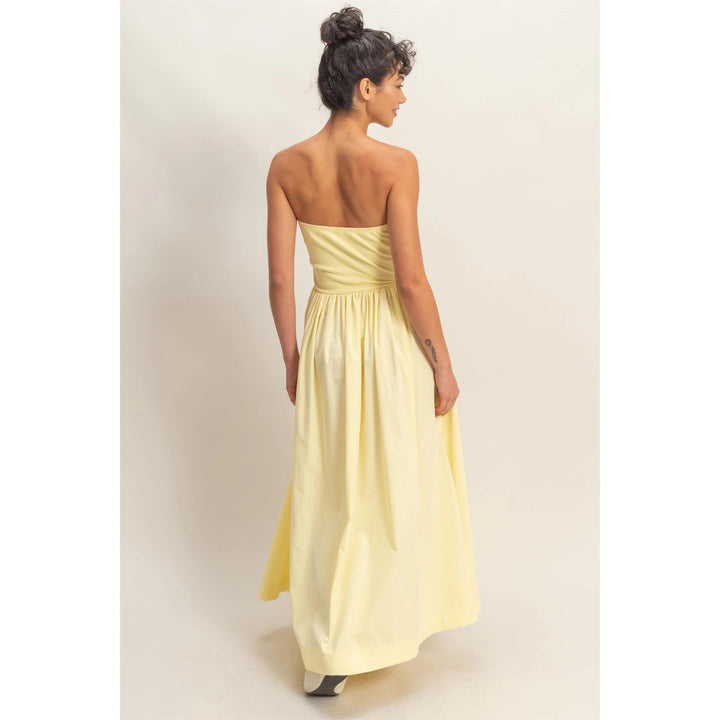 Woman wearing a strapless yellow dress against a plain background