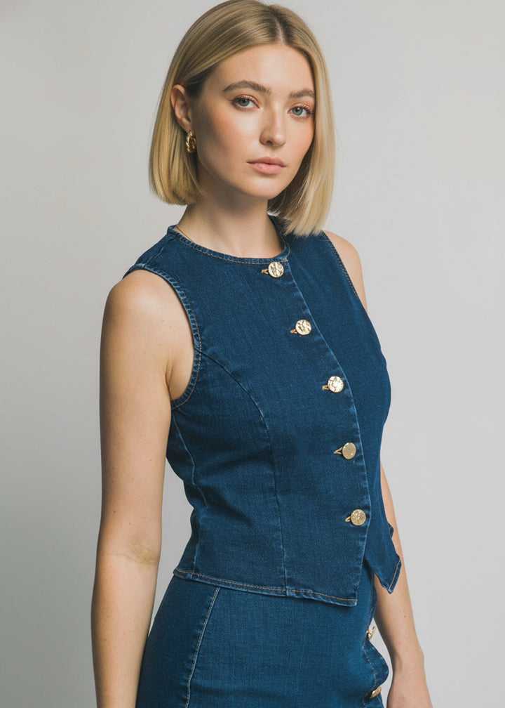 Woman wearing a blue denim dress with gold buttons on a gray background