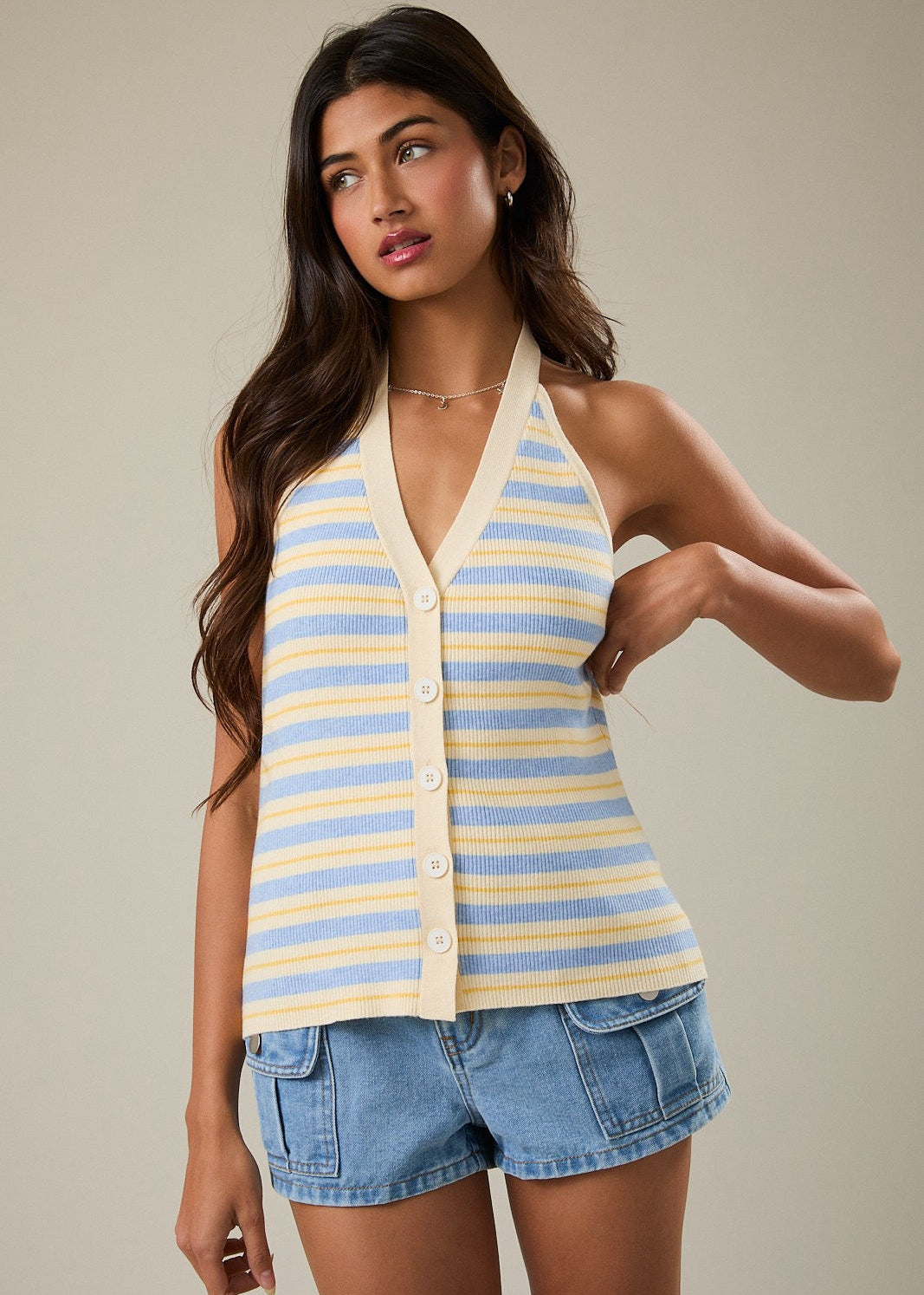 Woman wearing a striped halter top and denim shorts against a neutral background
