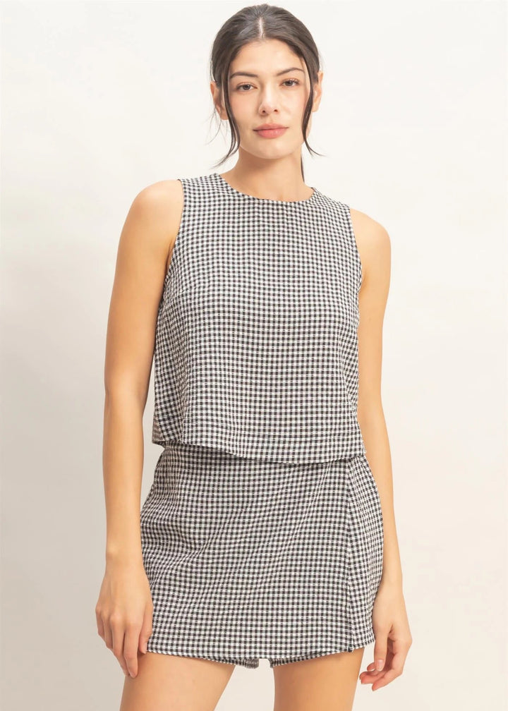Woman wearing a black and white checkered sleeveless top and skirt on a beige background