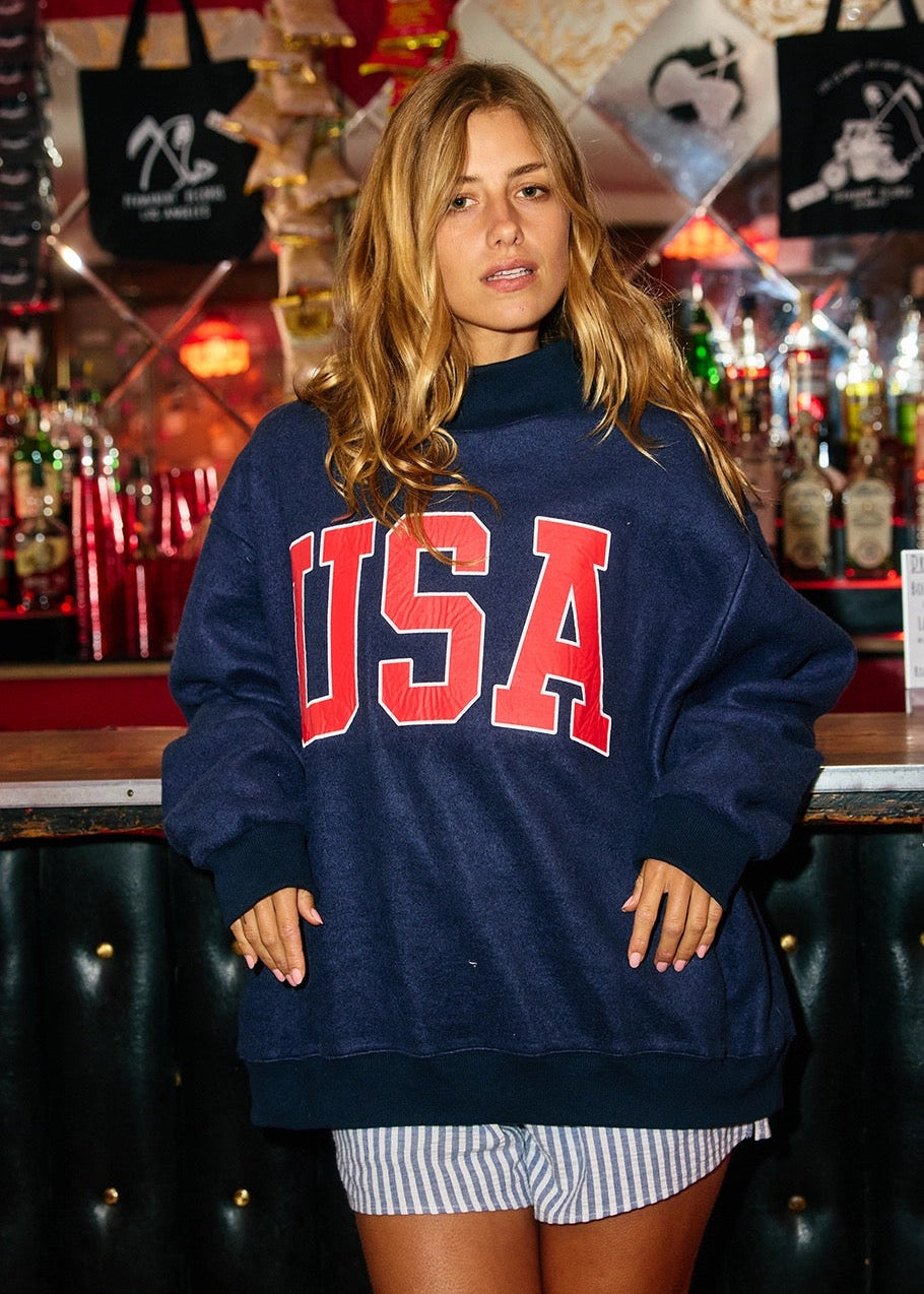 Person wearing a navy blue 'USA' sweatshirt in a bar setting